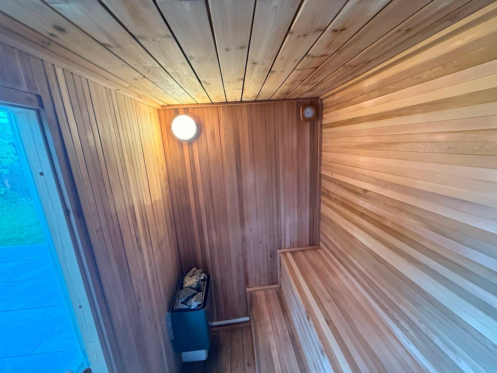 Warm cedar interior of the 2 man sauna with benches and heater